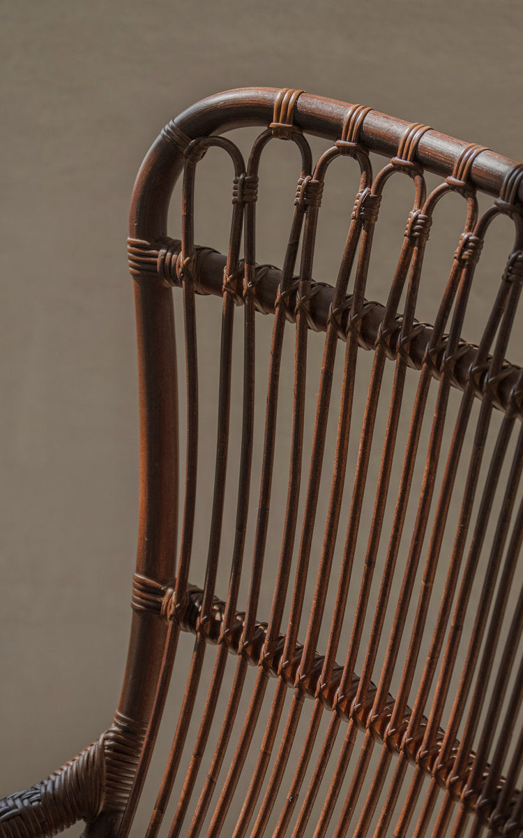 Dies ist ein Nahaufnahmebild von Monet Lounge-Sessel in brown rattan. Rückenlehne mit Bögen und senkrechten Rattanstreben.