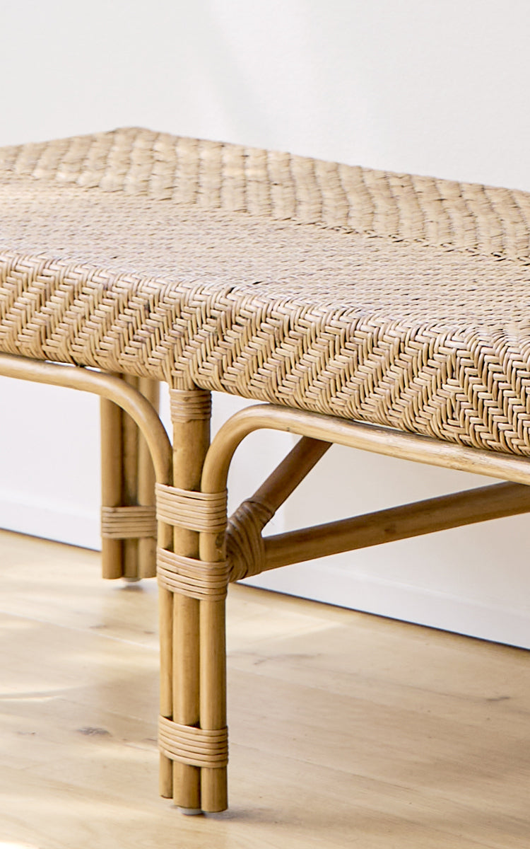 Dies ist ein Nahaufnahmebild von Luis Bank in antique rattan. Die fischgratgewebte Sitzfläche und die handgebundenen Rattanverbindungen zeigen die Handwerkskunst.