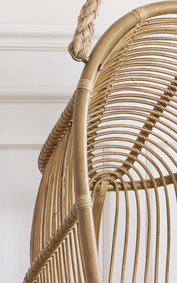 Dies ist ein Nahaufnahmebild von Renoir Hängesessel in antique rattan. Detail des geschwungenen Rattanrahmens mit radialen Speichen und Seilaufhängung.