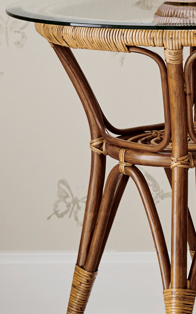 Dies ist ein Nahaufnahmebild von Tony Beistelltisch in antique rattan. Detail der Glasplattenkante mit umwickeltem Rattan und gebogenen Beinen.
