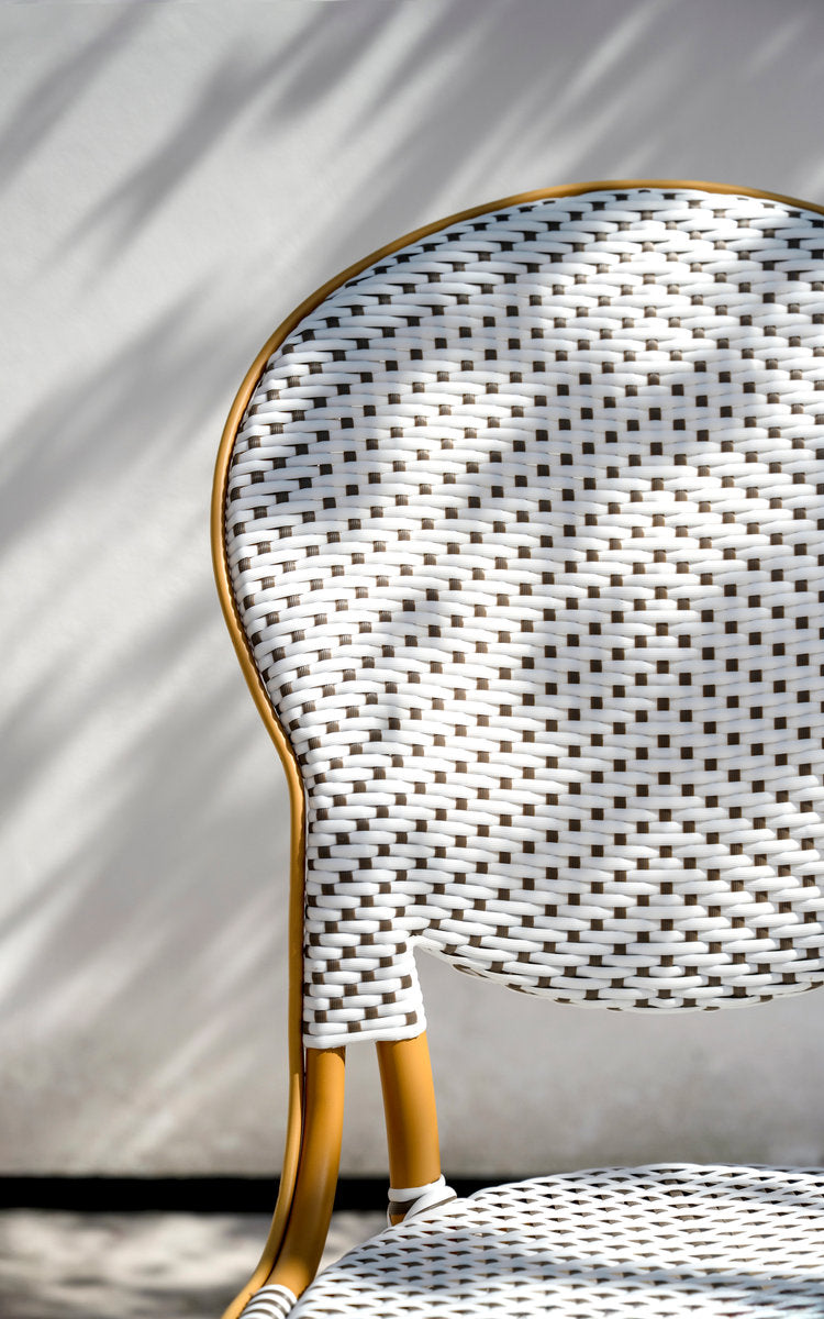 Dies ist ein Nahaufnahmebild von Isabell Außen-Esszimmerstuhl in almond aluminium frame white w cappuccino dot artfibre. Ovale geflochtene Rückenlehne im Sonnenlicht.