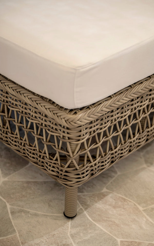 Dies ist ein Nahaufnahmebild von Mona Außen-Modulsofa-Pouf Module in antique grey artfibre aluminium. Geflochtene Poufkante mit weißem Kissen.