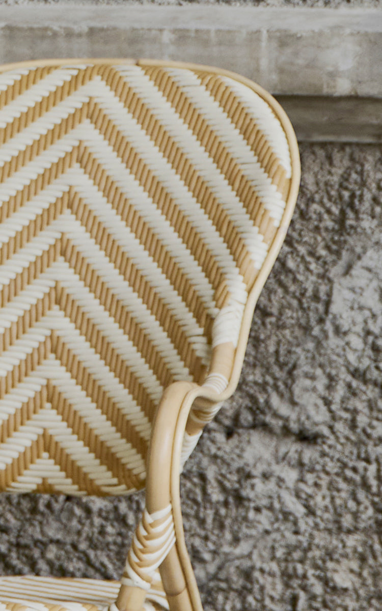 Dies ist ein Nahaufnahmebild von Isabell Esszimmer-Armlehnstuhl in chevron Honey Ivory ArtFibre Skin on Rattan frame.