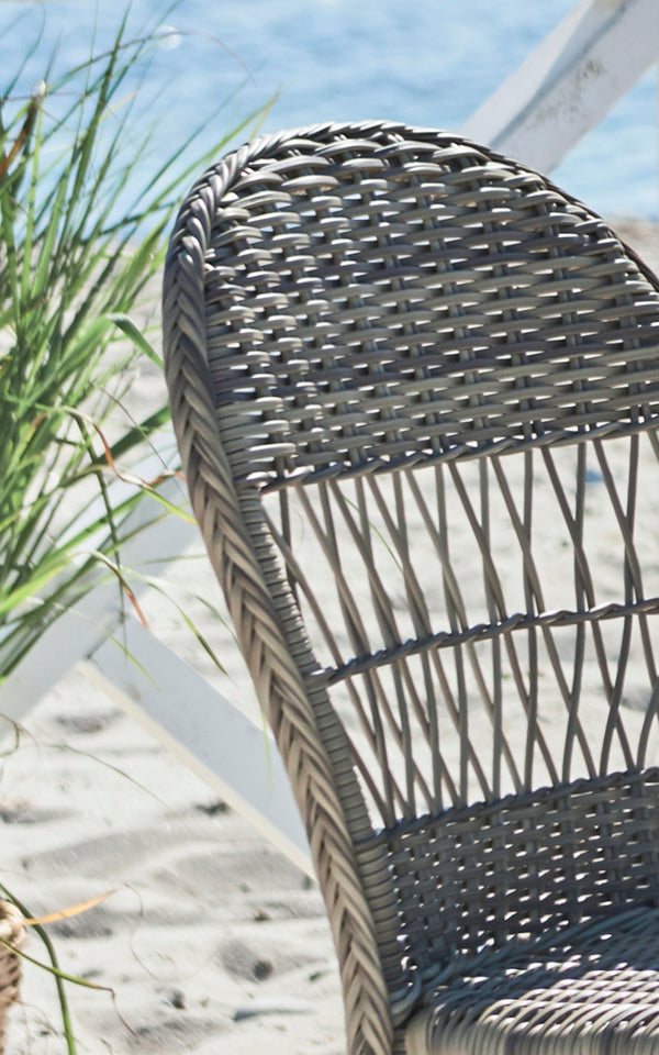 Dies ist ein Nahaufnahmebild von Ofelia Exterior Chair i antique grey artfibre aluminium. Detail der abgerundeten geflochtenen Rückenlehne und des Gestells.