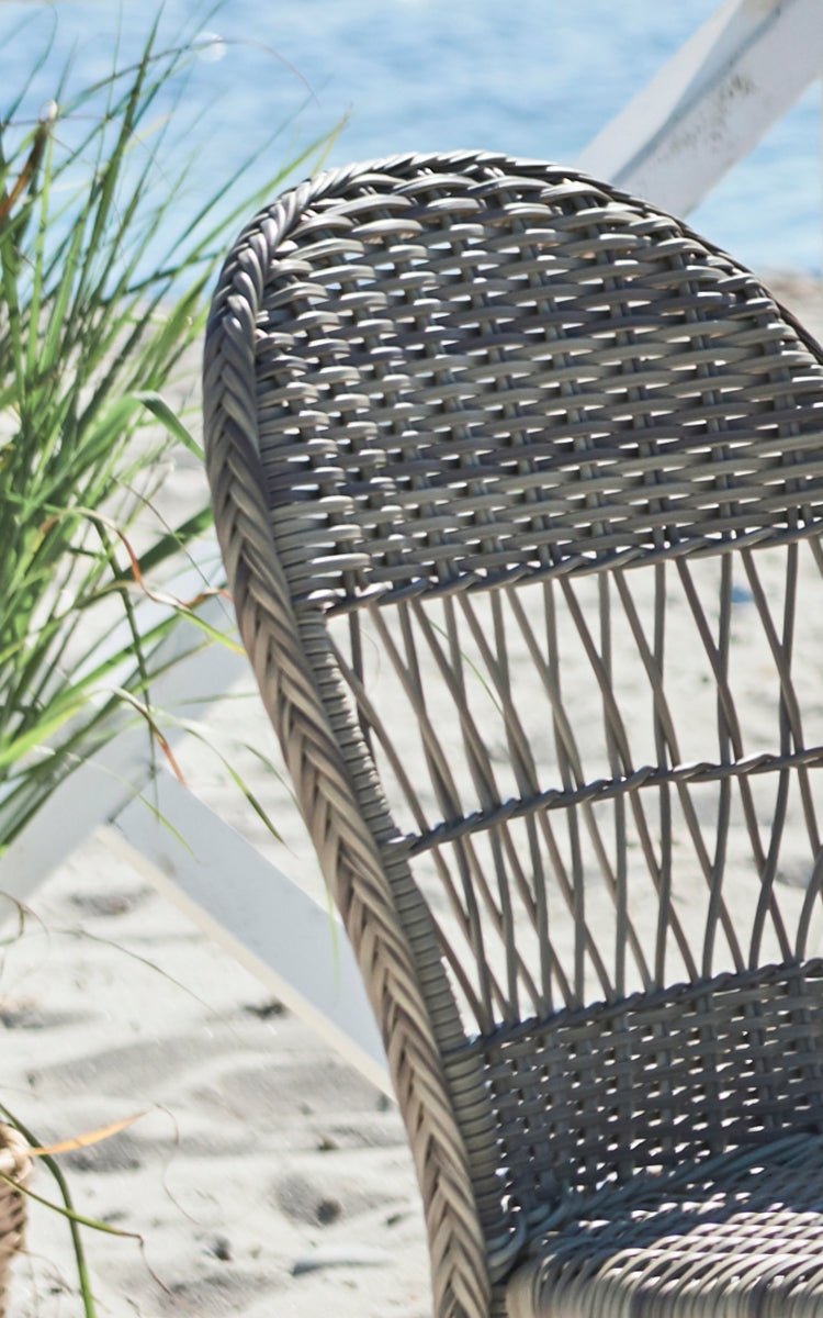 Dies ist ein Nahaufnahmebild von Ofelia Exterior Chair i antique grey artfibre aluminium. Detail der abgerundeten geflochtenen Rückenlehne und des Gestells.