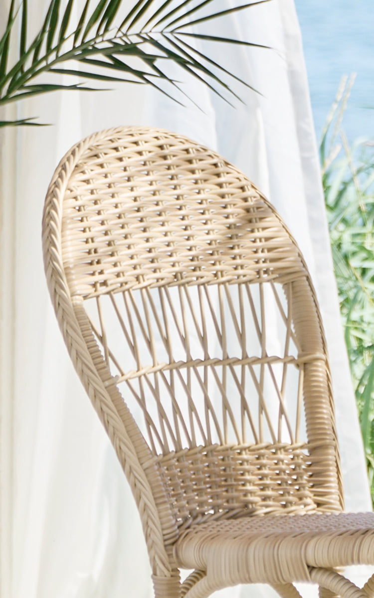 Dies ist ein Nahaufnahmebild von Ofelia Exterior Chair i natural artfibre aluminium. Detail der abgerundeten geflochtenen Rückenlehne und des Sitzgeflechts.