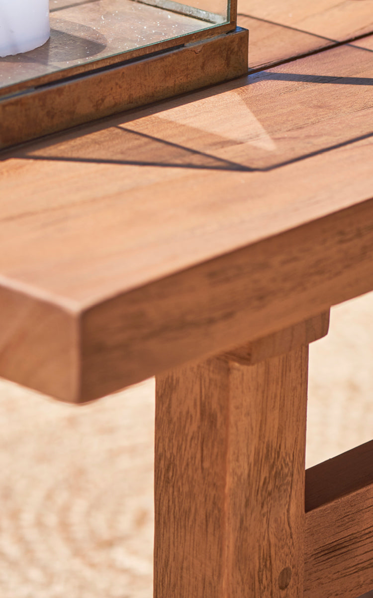 Dies ist ein Nahaufnahmebild von Julian Teak Lounge Table 140x55 cm in teak outdoor. Die dicke massive Teakkante und die robusten Beinverbindungen sind gezeigt.