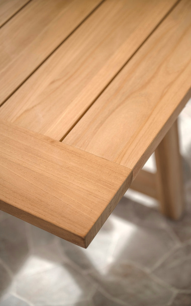 Dies ist ein Nahaufnahmebild von George Teak-Ausziehtisch 200-280x100 cm in teak outdoor. Glatte Teak-Tischkante und Bein.