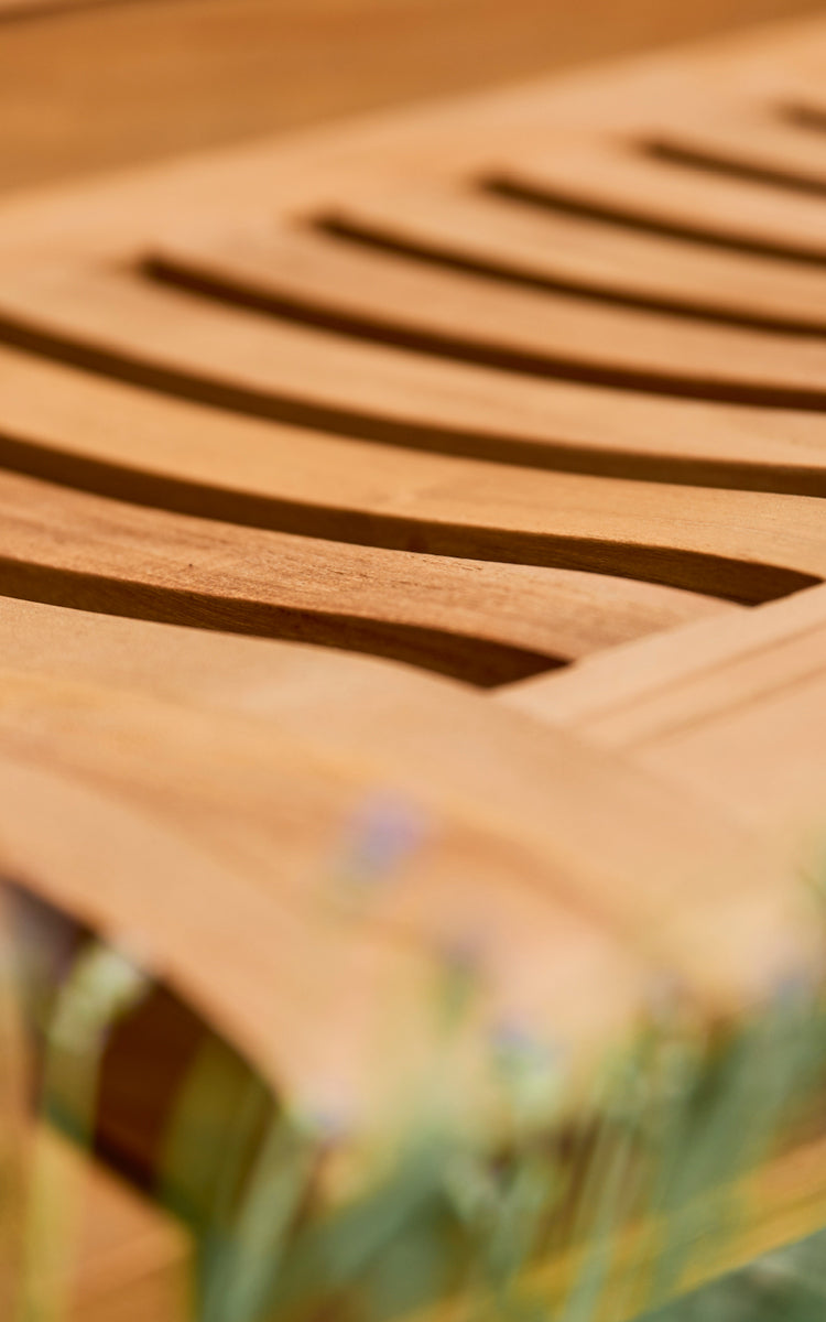 Dies ist ein Nahaufnahmebild von St Catherine Teakbank in teak outdoor. Detail der geschwungenen Teaklatten der Banksitzfläche.