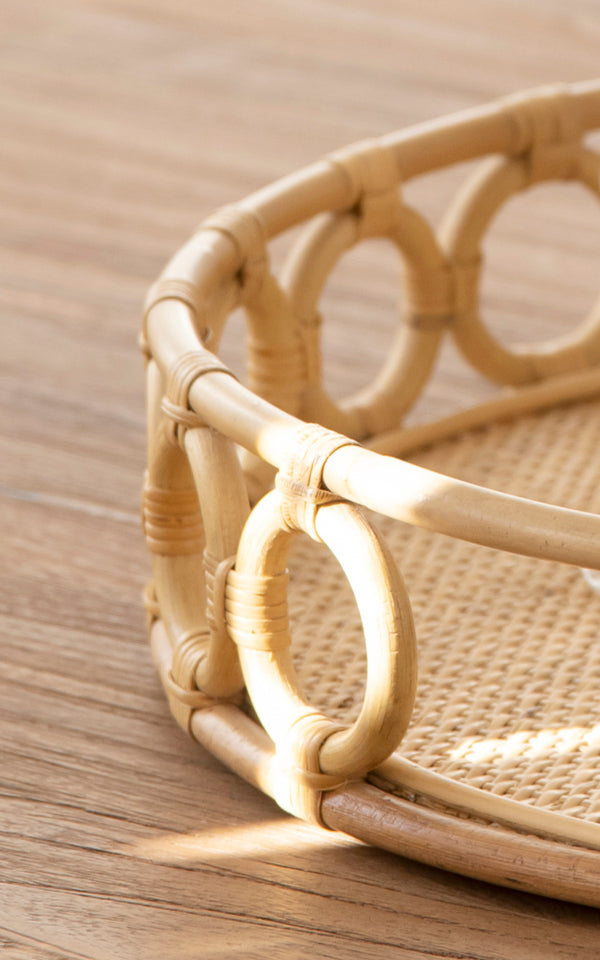 Dies ist ein Nahaufnahmebild von Mira Tray i natural rattan. Detail des kreisförmigen Ringrandes und des geflochtenen Rohrbasis des runden Tabletts.