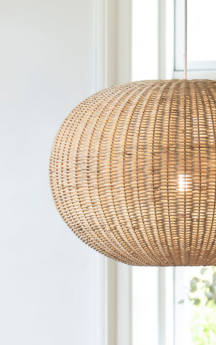 Dies ist ein Nahaufnahmebild von Tangelo Lampshade Ø62 cm | Large in natural rattan. Detail des großen Rattangeflechts des abgerundeten Pendels am Fenster.