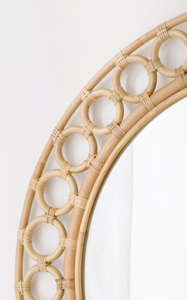Dies ist ein Nahaufnahmebild von Mira Mirror i natural rattan. Detail des kreisförmigen Rattanring-Rahmens um den runden Spiegel.