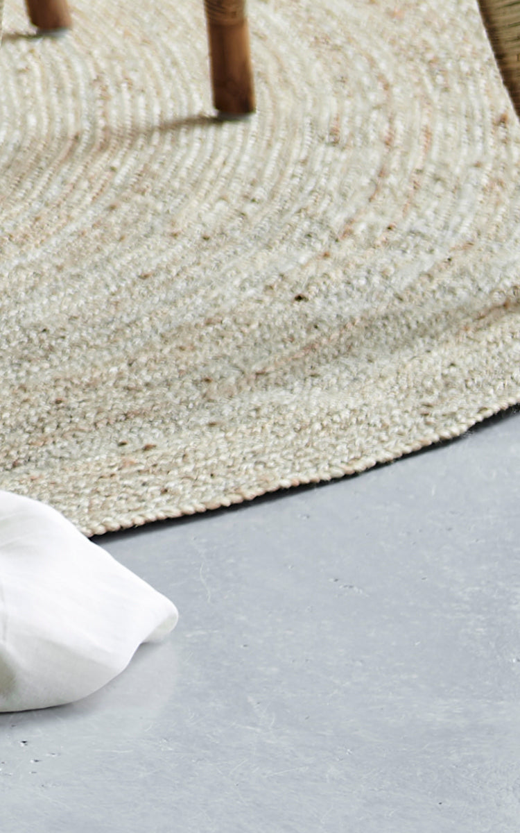 Dies ist ein Nahaufnahmebild von Jute Carpet Ø280 in grey jute. Die eng gewebte Textur und der abgerundete Rand sind auf einem Betonboden gezeigt.