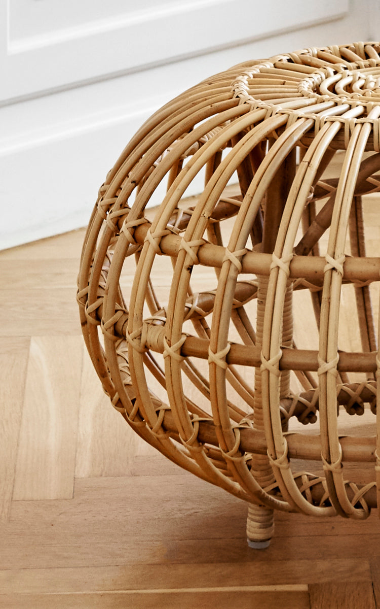 Dies ist ein Nahaufnahmebild von Ottoman Small in natural skin on rattan. Detail des offenen Rattankäfigs mit gebogenen Rippen und Kreuzbindungen.