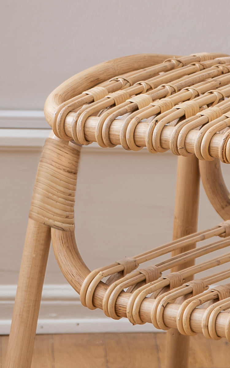 Dies ist ein Nahaufnahmebild von Machiya Hocker in natural skin on rattan. Geschlungenes Rattansitzgeflecht und umwickelte Rahmenverbindungen in warmen Tönen.