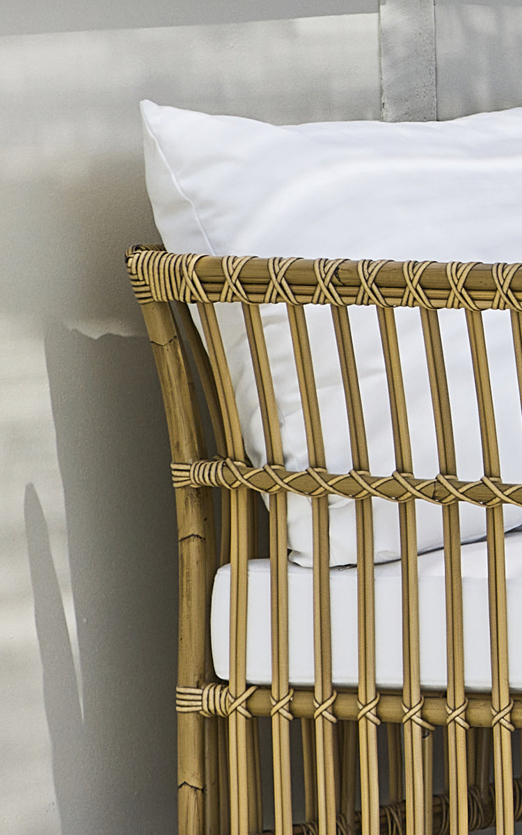 Dies ist ein Nahaufnahmebild von Maggie Sofa Eckmodul in antique aluminium artfibre. Vertikaler Lattenrahmen mit umwickelten Verbindungen und weißem Kissen.