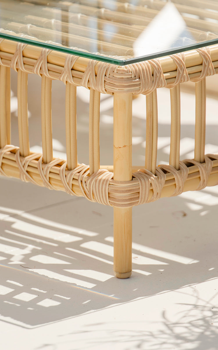 Dies ist ein Nahaufnahmebild von Maggie Sofa Pouf-Modul m. Glas in natural aluminium artfibre. Glasplatte auf Rattanrahmen mit umwickelten Verbindungen.