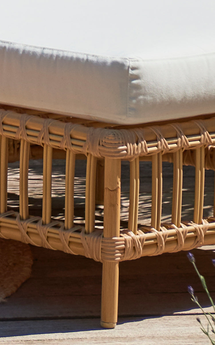 Dies ist ein Nahaufnahmebild von Maggie Sofa Pouf-Modul m. Glas in natural aluminium artfibre. Kissen auf Rattanrahmen mit umwickelter Lattendetail.