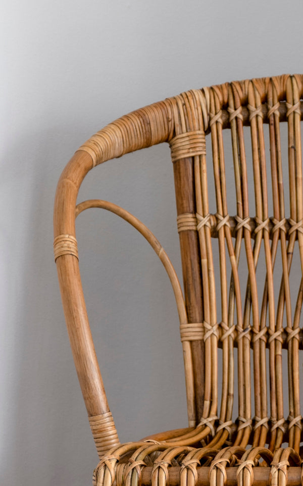Dies ist ein Nahaufnahmebild von Robert Esszimmerstuhl in polished antique rattan. Detail der geschwungenen Rattan-Armlehne und Sprossenrückenlehne mit umwickelten Verbindungen.