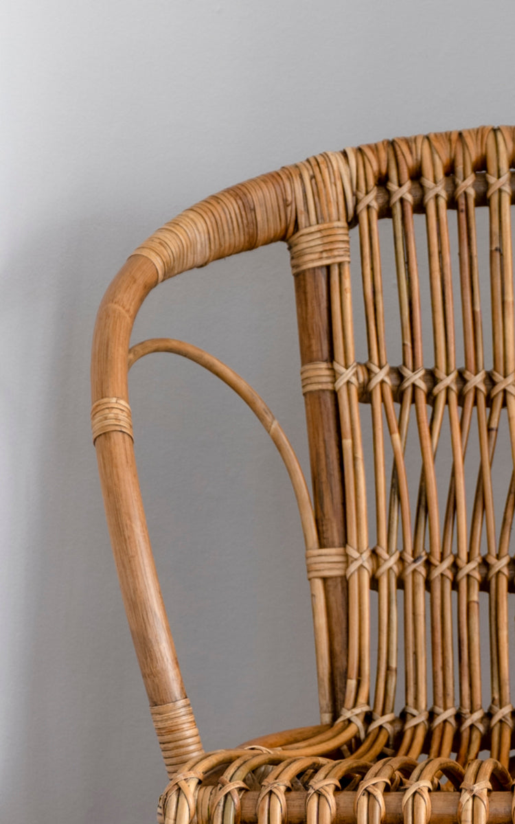 Dies ist ein Nahaufnahmebild von Robert Esszimmerstuhl in polished antique rattan. Detail der geschwungenen Rattan-Armlehne und Sprossenrückenlehne mit umwickelten Verbindungen.