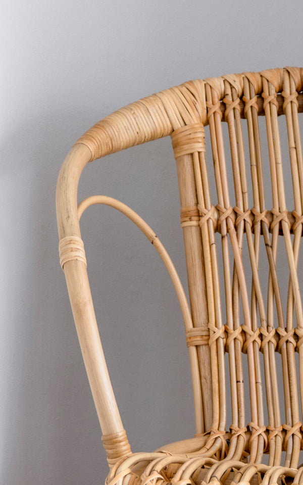 Dies ist ein Nahaufnahmebild von Robert Esszimmerstuhl in polished natural rattan. Detail der natürlichen gebogenen Rattan-Armlehne und Sprossenrückenlehne.