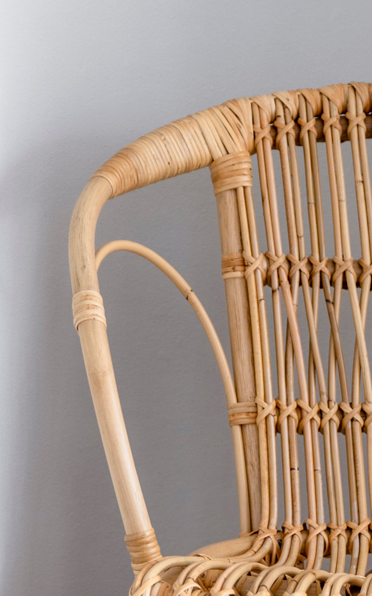 Dies ist ein Nahaufnahmebild von Robert Esszimmerstuhl in polished natural rattan. Detail der natürlichen gebogenen Rattan-Armlehne und Sprossenrückenlehne.