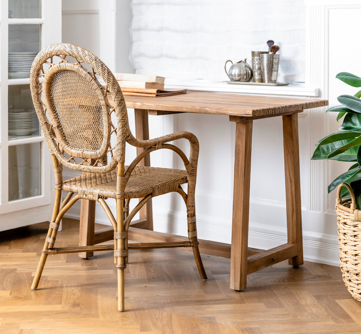 Dies ist ein Lifestyle-Bild von Romantica Esszimmerstuhl in antique rattan. In einer grauen Stein-Innenwand mit schmiedeeisernen Wandlampen arrangiert.