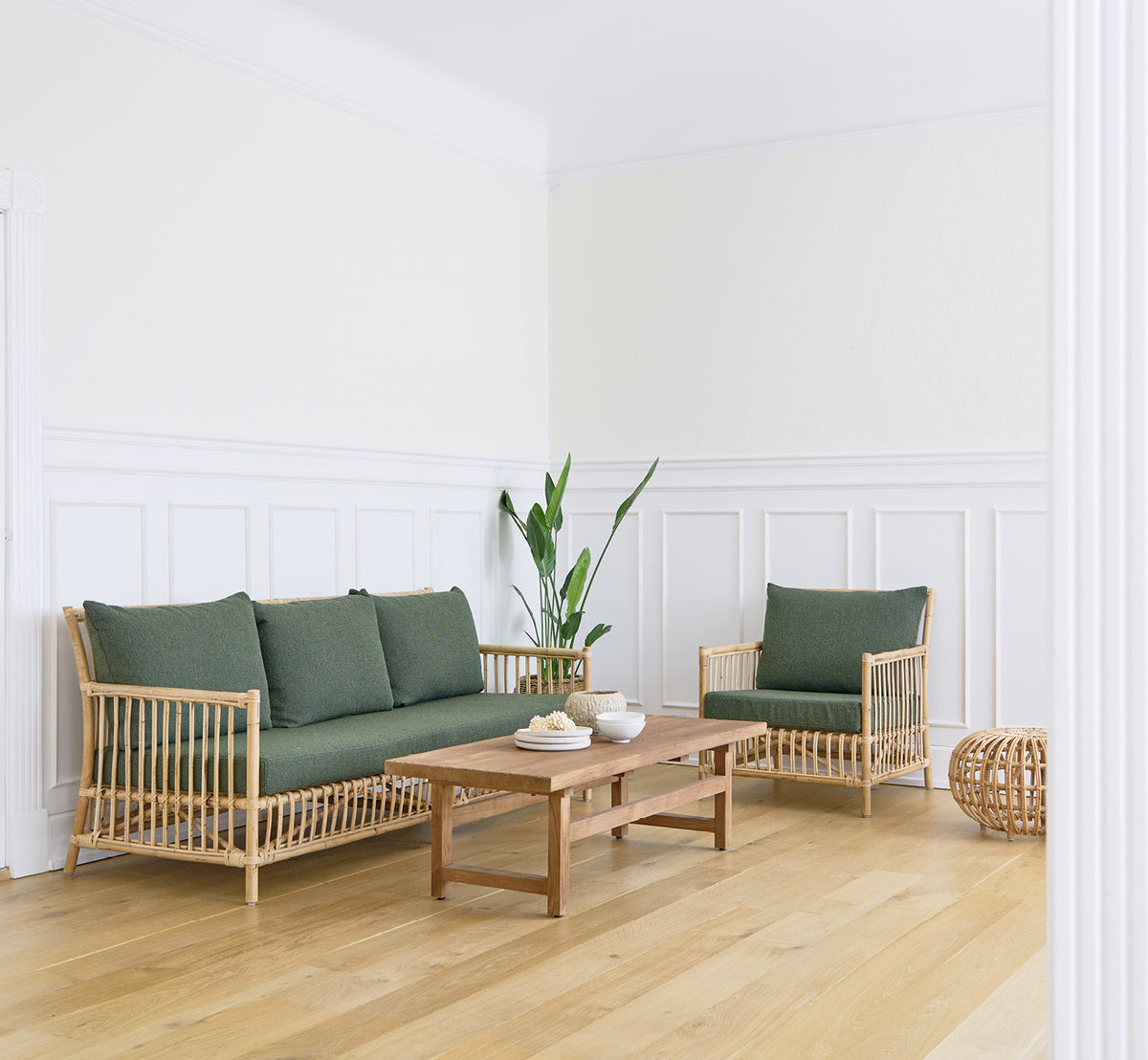Dies ist ein Lifestyle-Bild von Caroline Lounge-Sessel in natural rattan, in einem hellen skandinavischen Wohnzimmer mit Fischgrätparkett.