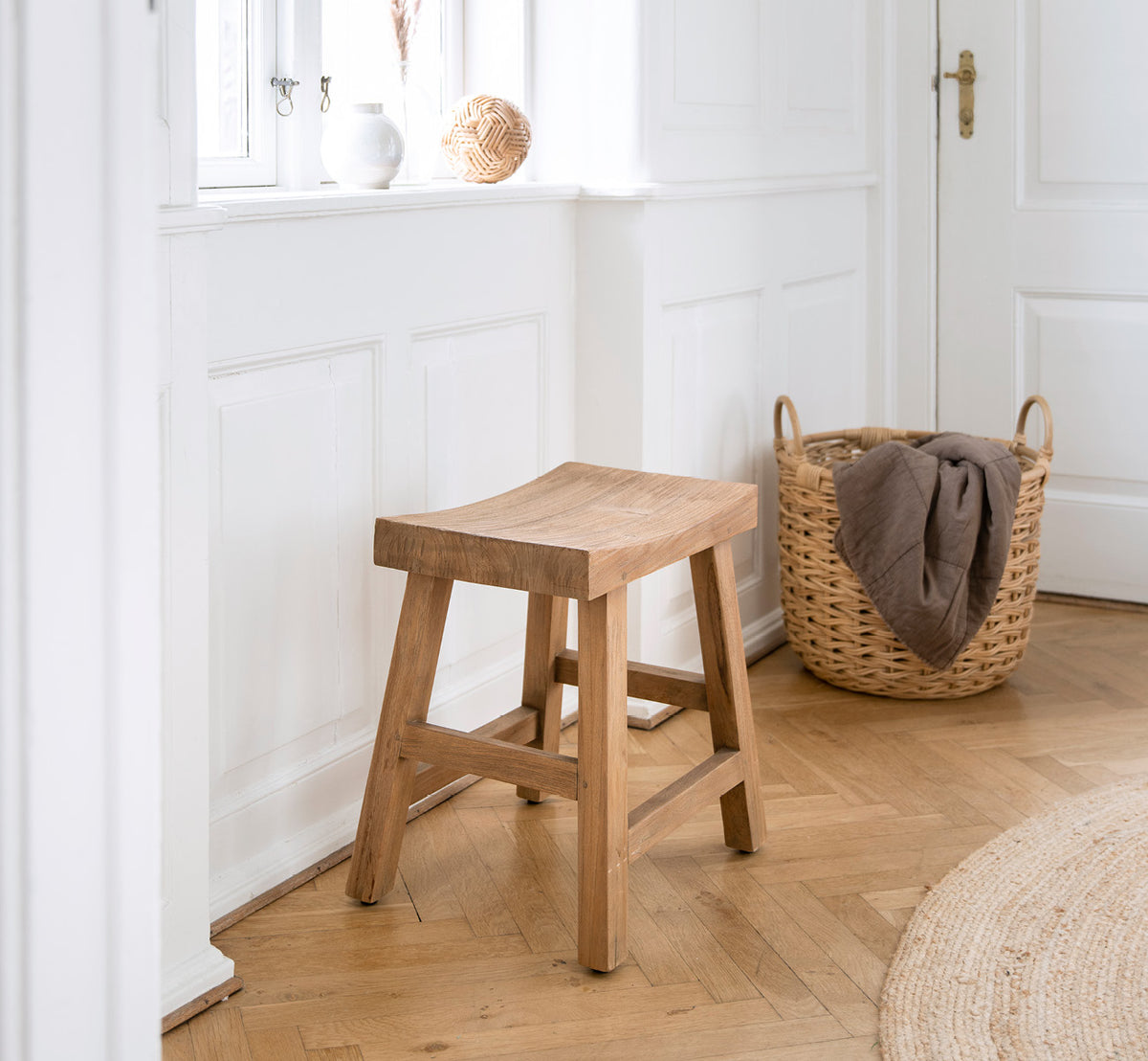 Dies ist ein Lifestyle-Bild von Charles Hocker in teak indoor, in einem hell-weißen Interieur mit Wandvertäfelung und Fischgrätparkett.