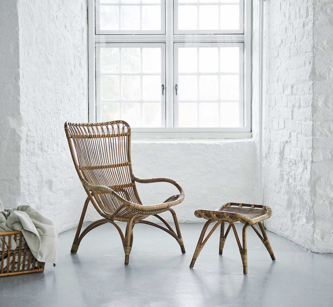 Dies ist ein Lifestyle-Bild von Monet Lounge Chair i antique rattan. In einem Raum mit Schmetterlings-Tapete und dekorativen marokkanischen Laternen.