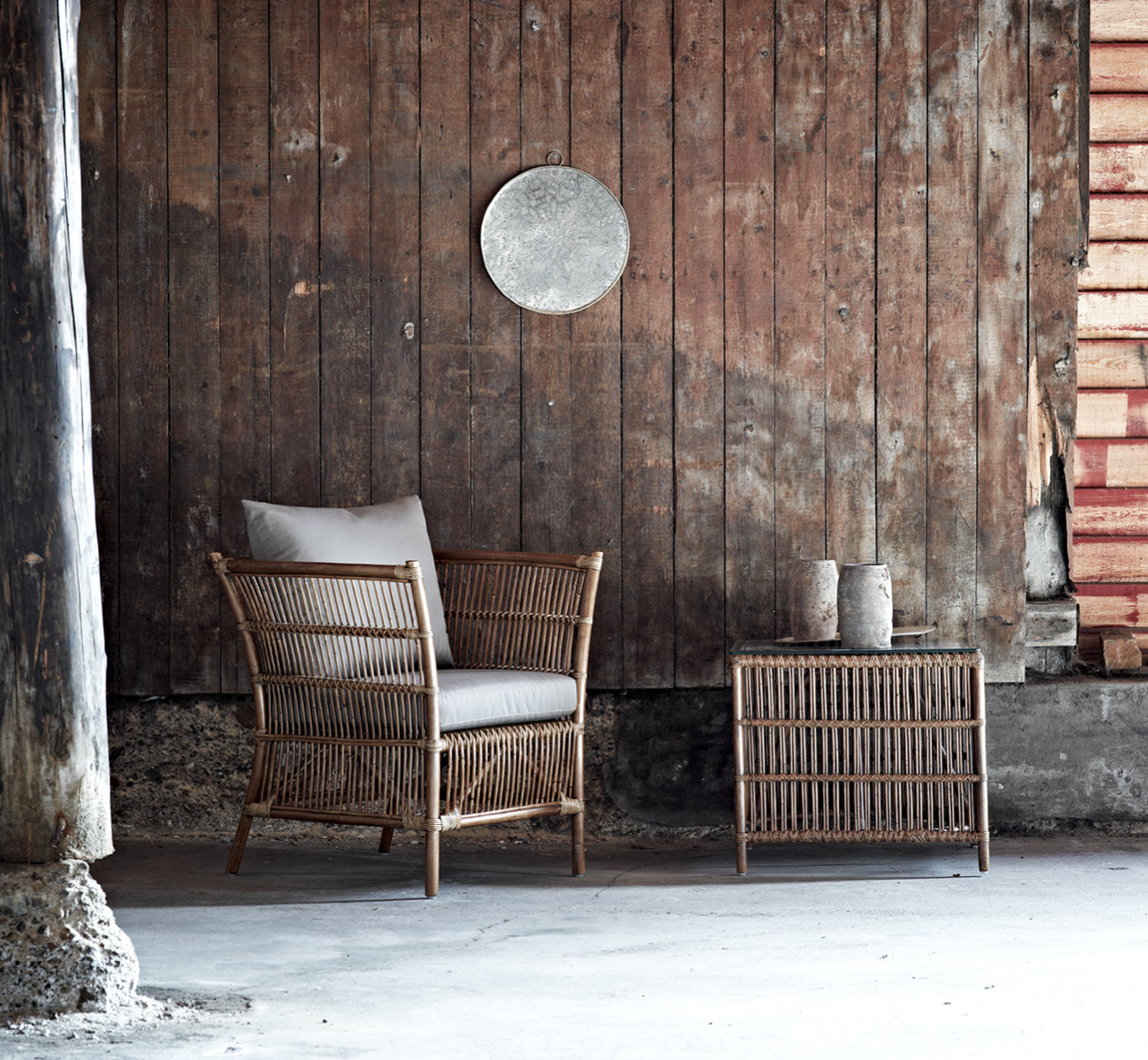 Dies ist ein Lifestyle-Bild von Donatello Beistelltisch in antique rattan, in einem hellen Interieur mit weißen Wandpaneelen und Fischgrätparkett.