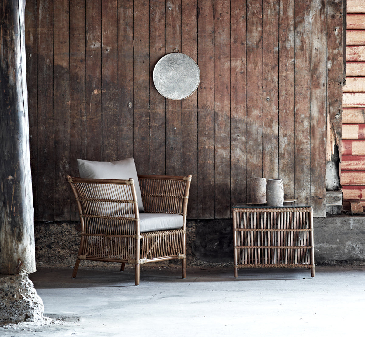 Dies ist ein Lifestyle-Bild von Donatello Beistelltisch in antique rattan, in einem hellen Interieur mit weißen Wandpaneelen und Fischgrätparkett.