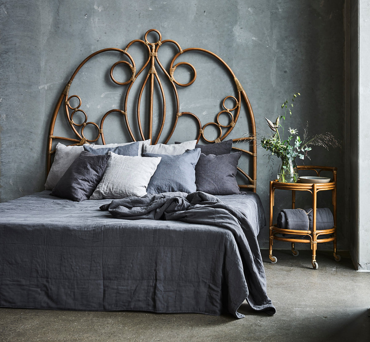 Dies ist ein Lifestyle-Bild von Natalia Kopfteil in antique rattan, in einem ruhigen hellen Schlafzimmer mit neutralem Leinen und Fischgrätparkett.