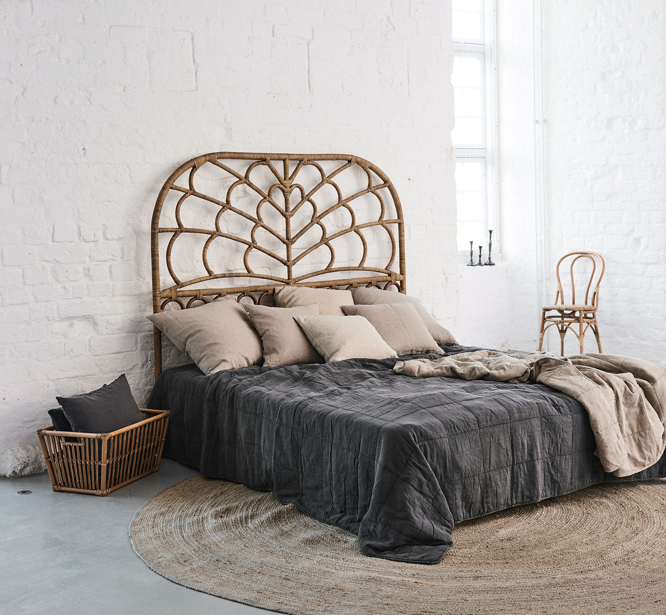 Dies ist ein Lifestyle-Bild von Celia Kopfteil in antique rattan, in einem ruhigen hellen Schlafzimmer mit neutralem Leinen und Fischgrätparkett.