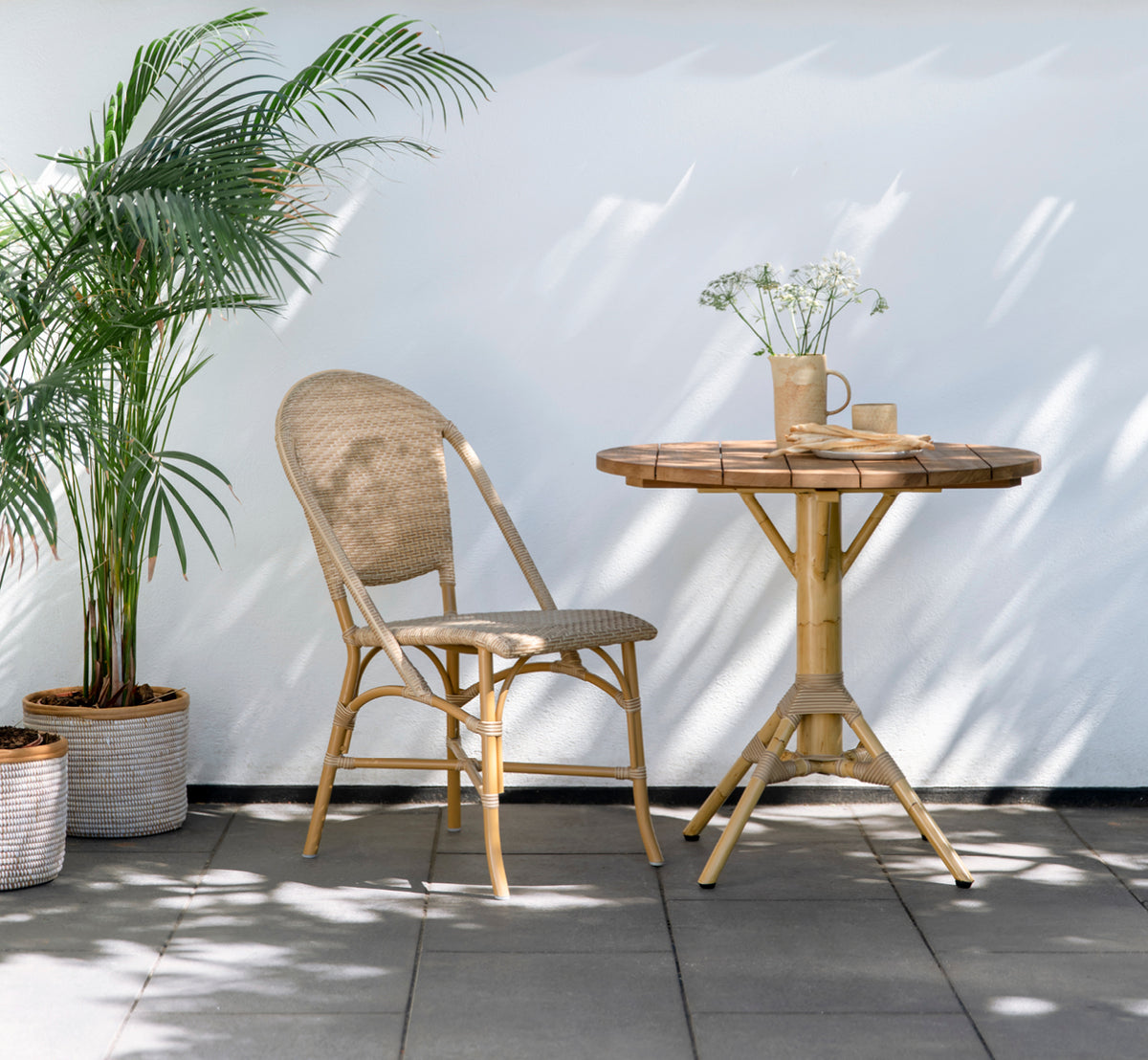 Dies ist ein Lifestyle-Bild von Sofie Exterior Dining Chair i almond aluminium frame natural ArtFibre. Auf einer mediterranen Terrasse.