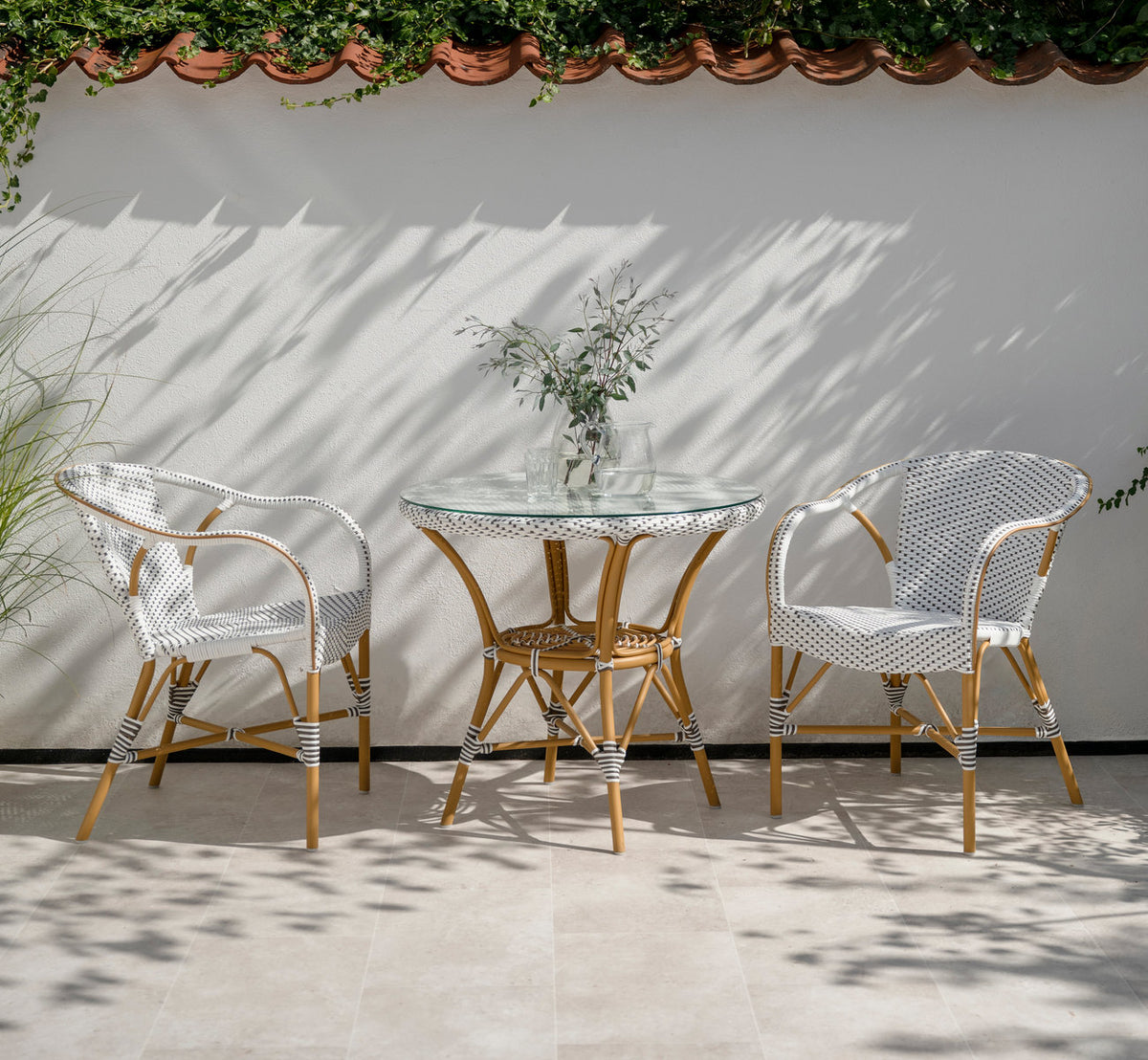Dies ist ein Lifestyle-Bild von Danielle Außen-Cafétisch in almond aluminium frame white w cappuccino dot artfibre. Mit Stühlen auf einer sonnigen Terrasse.