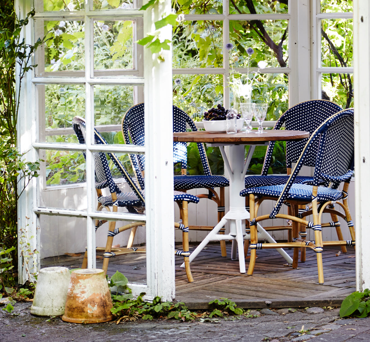 Dies ist ein Lifestyle-Bild von Sofie Esszimmerstuhl in navy blue w white dot artfibre skin on rattan frame. In einem hellen Interieur gestylt.