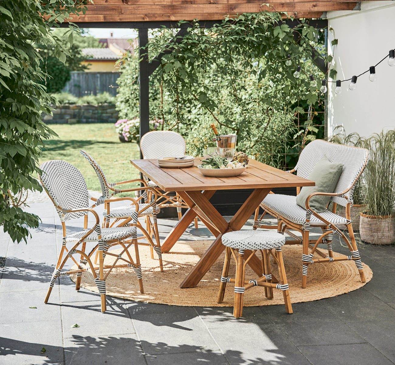 Dies ist ein Lifestyle-Bild von Isabell Esszimmer-Armlehnstuhl in white w cappuccino dot ArtFibre Skin on Rattan frame, in einem hellen Essbereich.