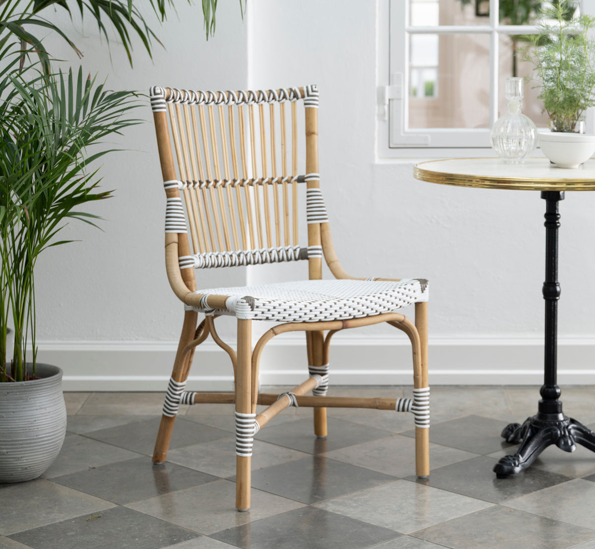 Dies ist ein Lifestyle-Bild von Monique Esszimmerstuhl in white w cappuccino dot artfibre skin on rattan frame. In einem hellen Interieur gestylt.