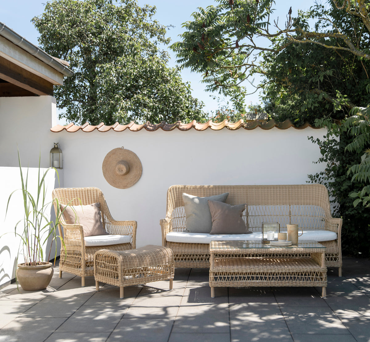 Dies ist ein Lifestyle-Bild von Dawn Sofa in natural ArtFibre Aluminium, auf einer Küstenterrasse mit weißem Holzdeck und Meerblick.