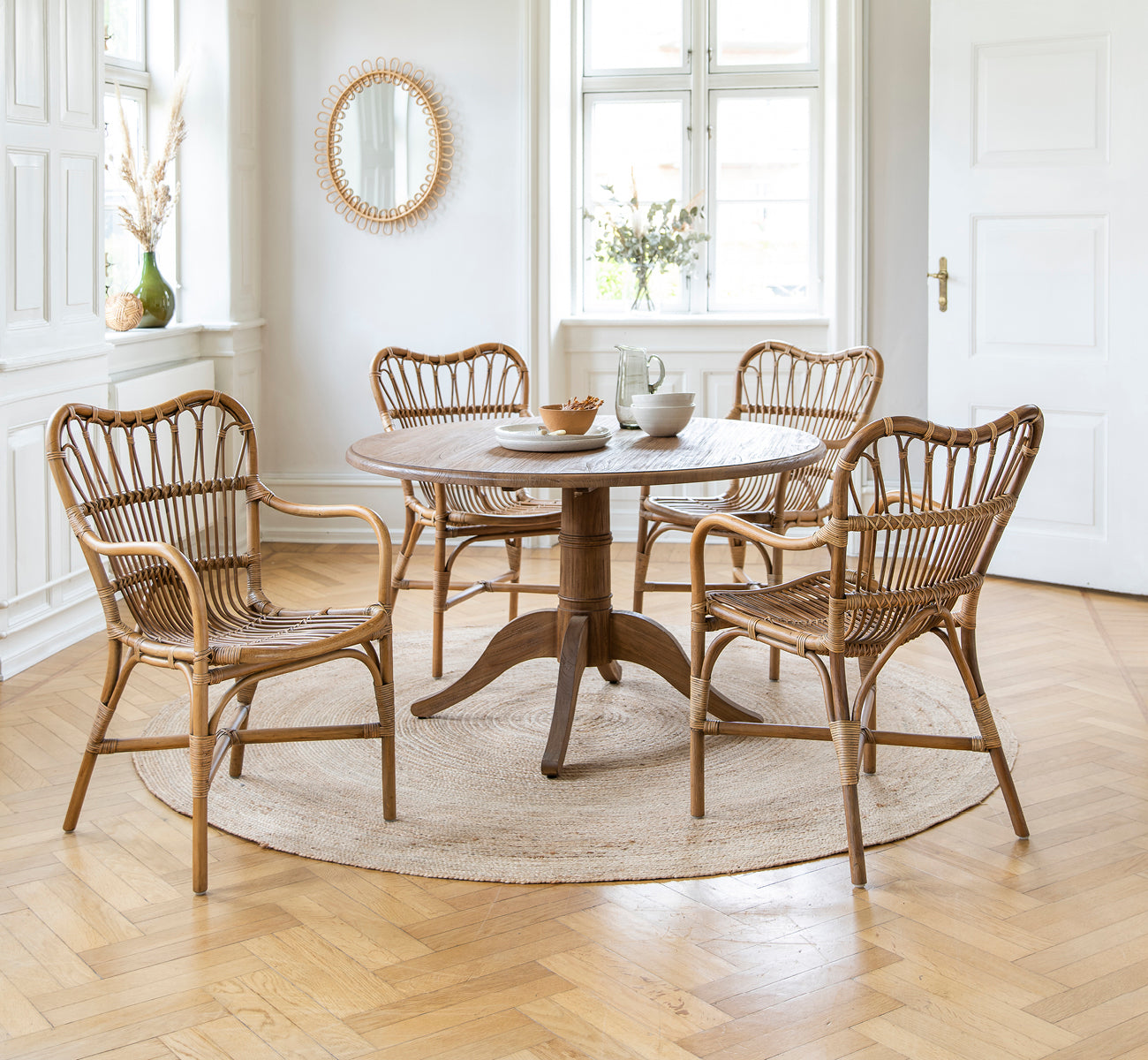 Dies ist ein Lifestyle-Bild von Michel Teak Dining Table i teak indoor. Mit Rossini-Stühlen auf einem Juteteppich in einem hellen weißen Loft.
