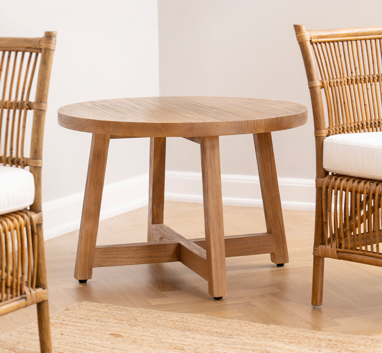 Dies ist ein Lifestyle-Bild von Aksel Couchtisch in teak indoor, in einem hellen Interieur mit Fischgrätparkett und Rattanstühlen.
