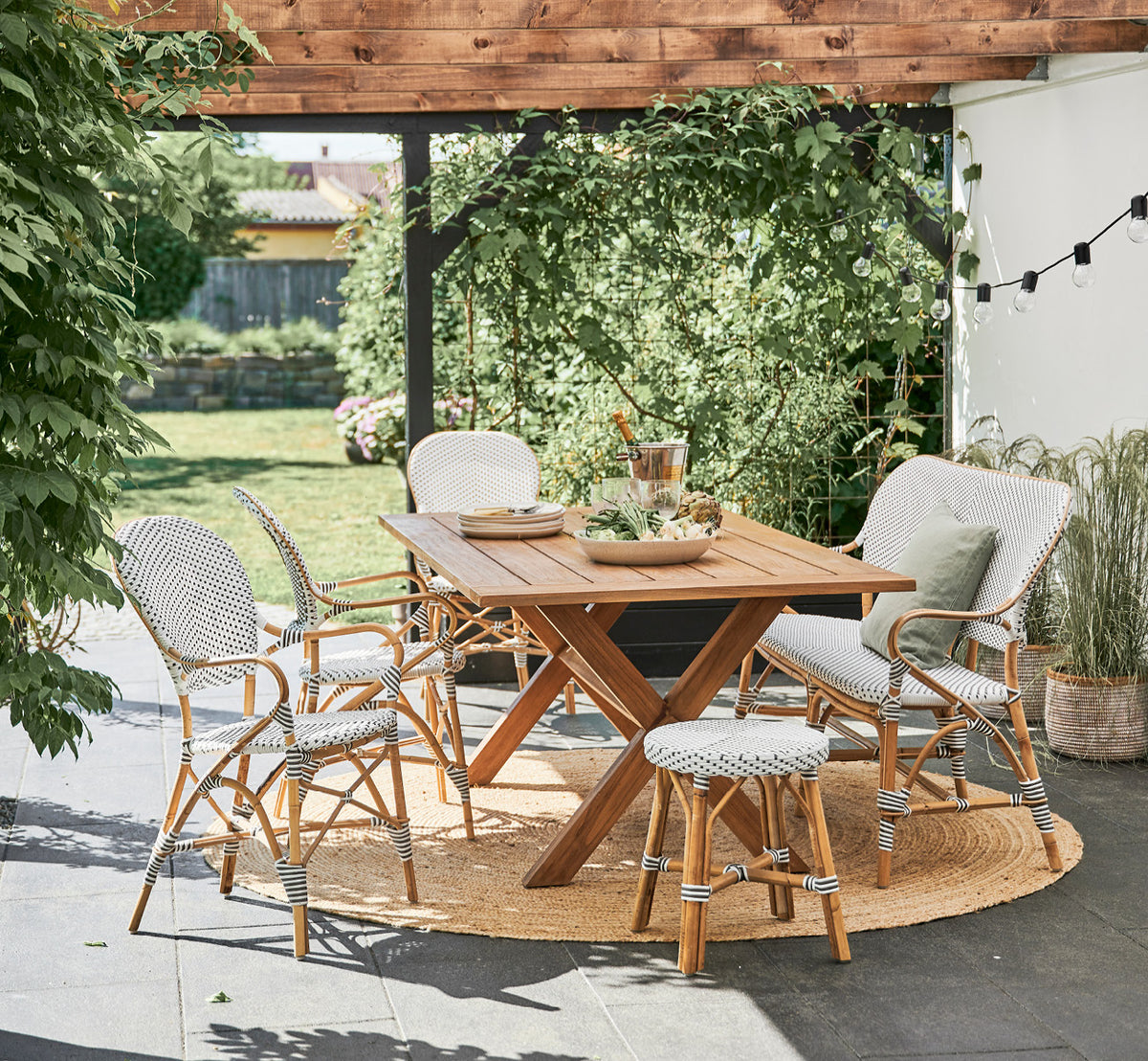 Dies ist ein Lifestyle-Bild von Colonial Tisch 160 in outdoor Teak, auf einer Strandterrasse mit weißem Holzdeck und Meerblick.