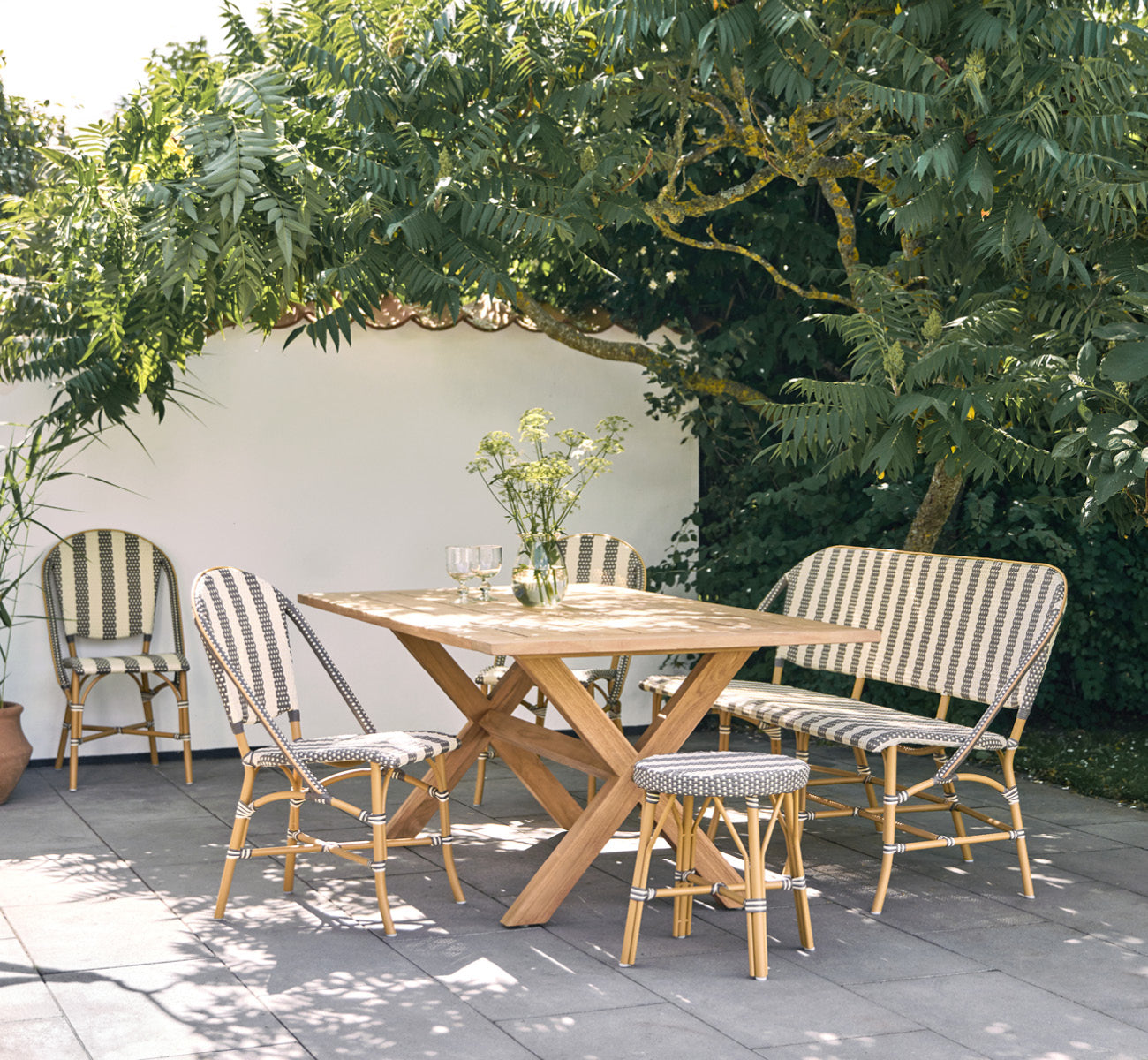 Dies ist ein Lifestyle-Bild von Colonial Tisch 160 in outdoor Teak, auf einer Strandterrasse mit weißem Holzdeck und Meerblick.