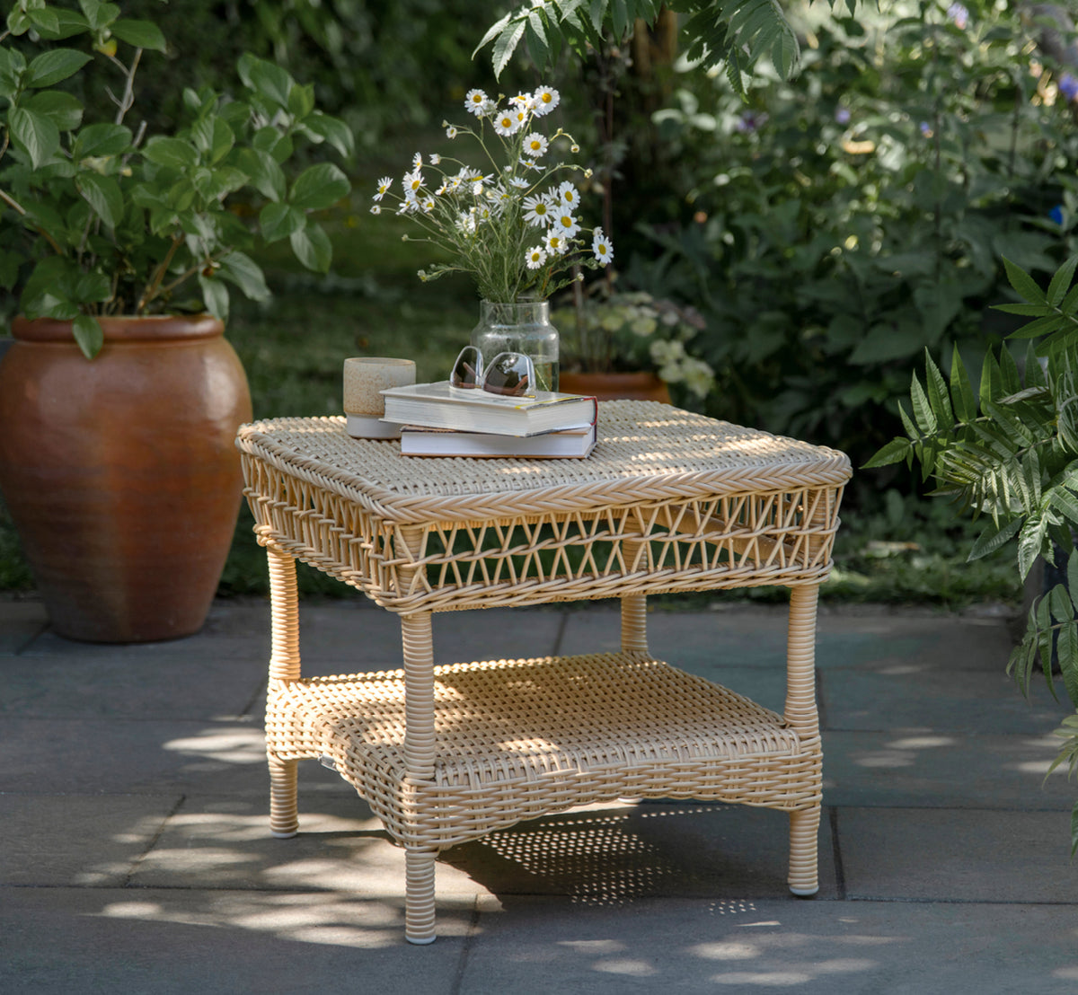 Dies ist ein Lifestyle-Bild von Susy Beistelltisch in natural ArtFibre Aluminium, auf einer Küstenterrasse mit Meerblick, Strandgräsern und weißen.