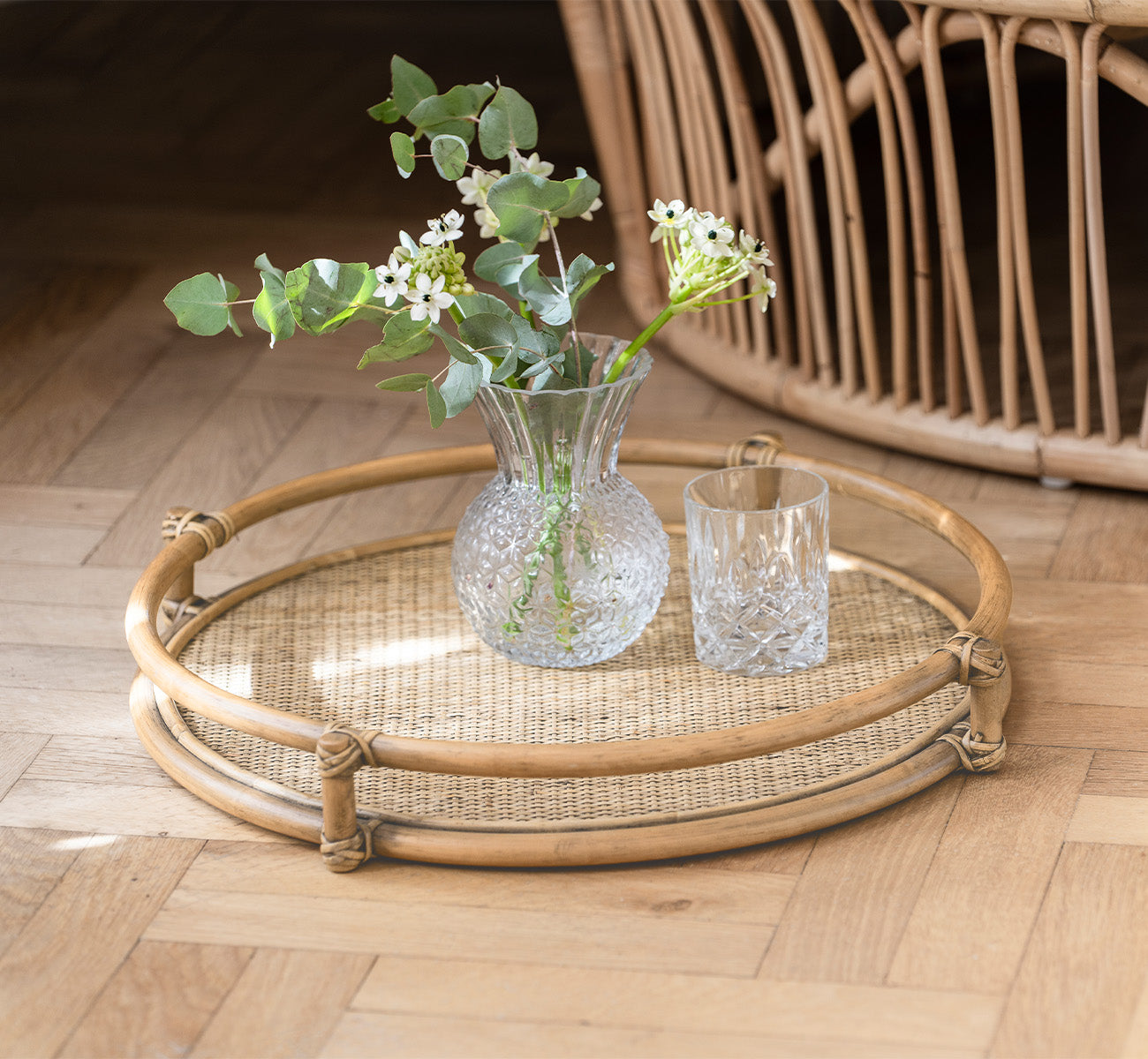 Dies ist ein Lifestyle-Bild von Andreas Tablett in natural Rattan, in einem hellen Interieur mit Fischgrätparkett.