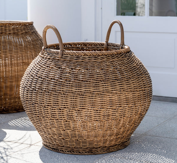 Dies ist ein Lifestyle-Bild von Smilla Korb in chestnut core weave ArtFibre Aluminium, im Freien auf einer sonnigen Terrasse mit weißer Mauer und.
