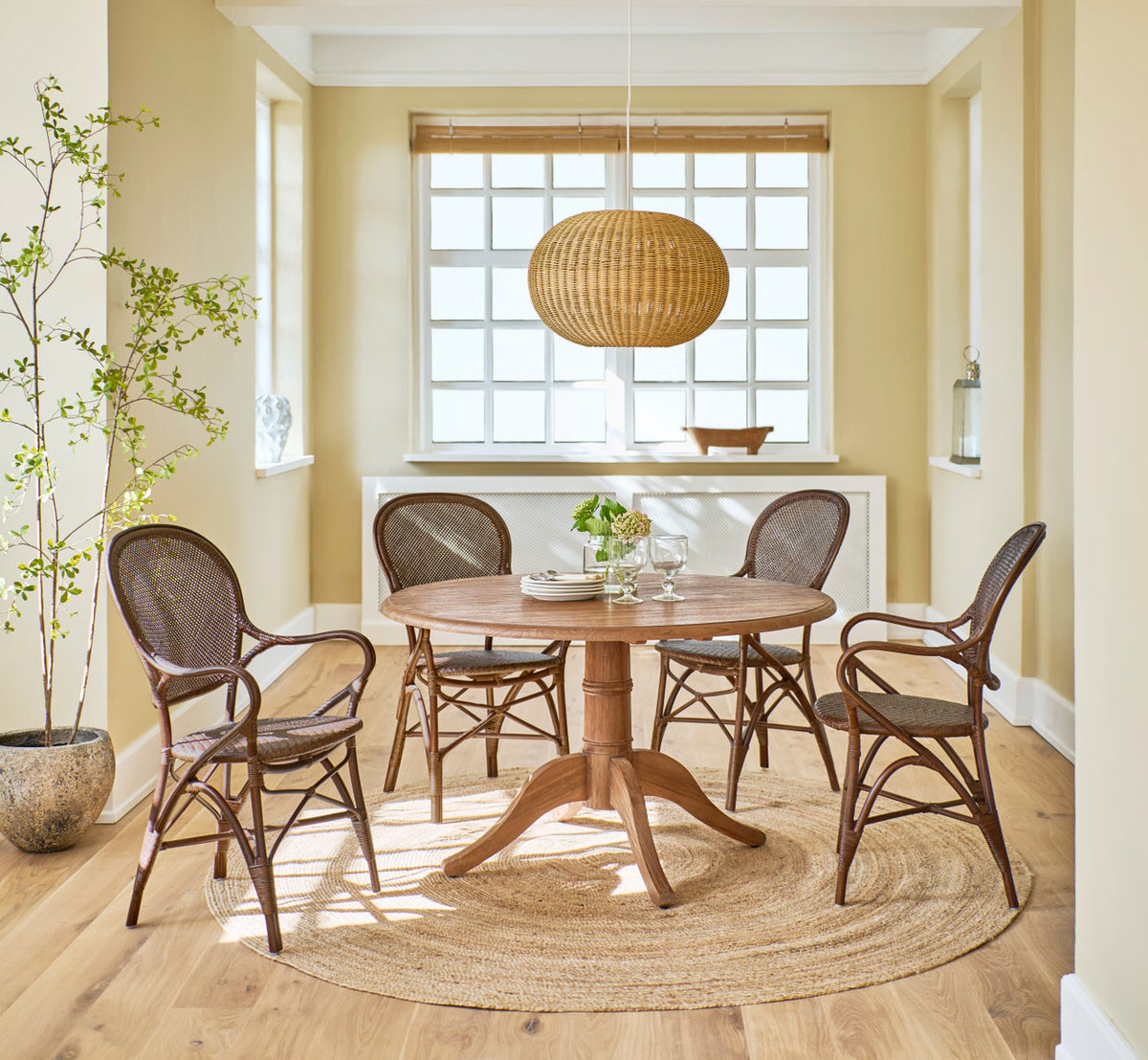Dies ist ein Lifestyle-Bild von Tangelo Lampenschirm Ø49 cm-Medium in natural core weave iron frame. Über einem runden Teaktisch mit Rattanstühlen.
