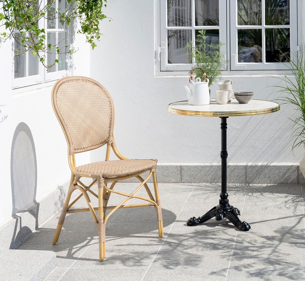 Dies ist ein Lifestyle-Bild von Lyon Cafétisch Versalite Marble Ø70 cm in cast iron. Innenhof mit Essstuhl und Kaffeeset auf dem Tisch.