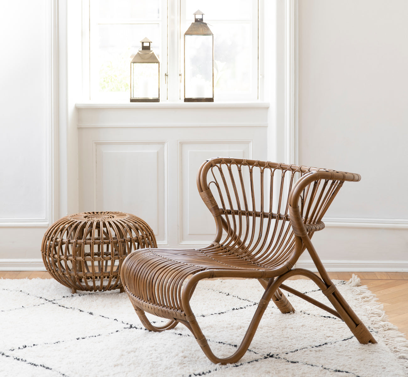 Dies ist ein Lifestyle-Bild von Ottoman Small in polished antique rattan. In einem Raum mit verzierter Tapete und einer klassischen Statue platziert.